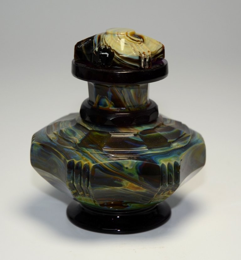 Lithyalin Perfume Bottle: Body and stopper made of a dark yellowish-green and amethyst marbled glass. Foot, collar, and top rim are amethyst glass and applied to body. Various cuts and facets. Possibly from Friedrich Egermann 