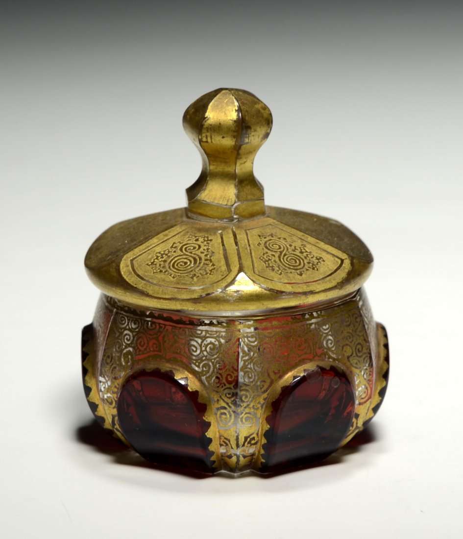 Mini Powder Box: Blown clear glass. Six raised panels stained ruby, facet-cuts to box, lid, and handle with gilt decoration. 2.25"ht., 2.0"wt., German. Circa 1900.