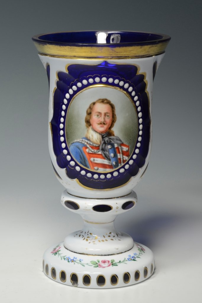 Double Overlay Beaker: Blown glass, white over clear over cobalt blue. Two raised white panels. Enameled with a soldiers portrait on front and flowers on rear and foot. Gilded leaf design. 7.0"ht., Bohemian, circa 1850