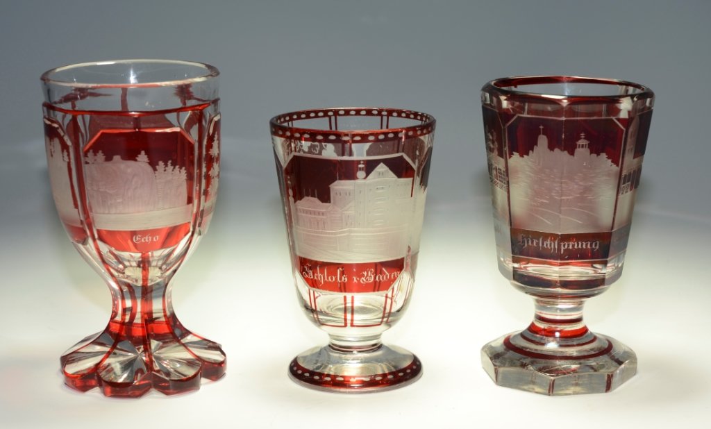 Group of Souvenir Spa Beakers: All are clear glass ruby stained, two are facet and wheel-cut. Each has panels with engraved spa and town scenes. 4.5"ht., 4.25"ht., 3.75"ht., Bohemian, circa 1880.