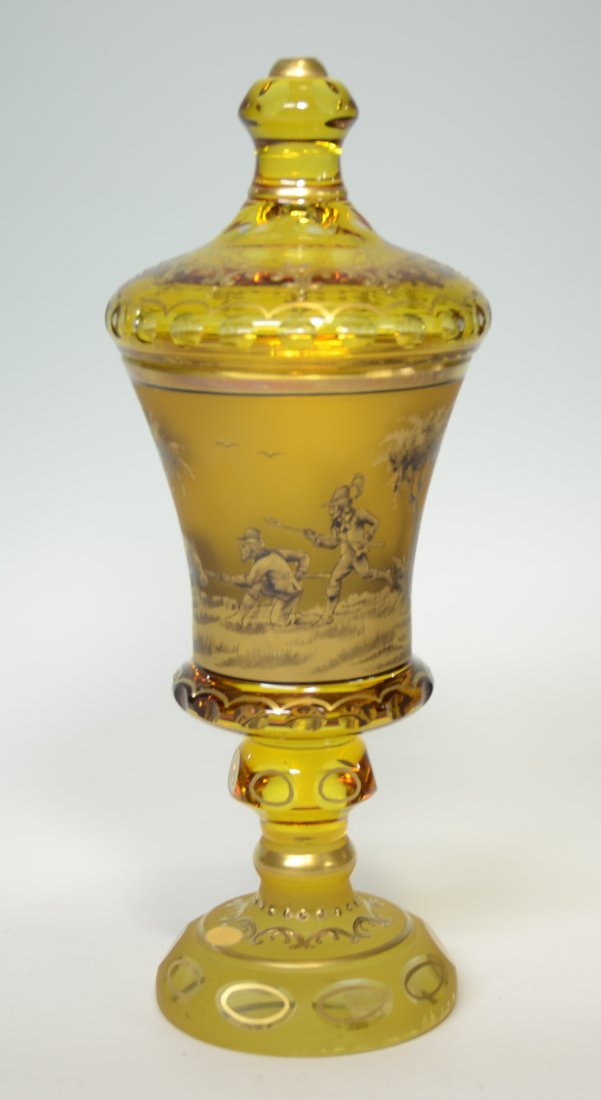 Amber Stained Pokal: Blown clear glass, oval facet-cut and amber stained. Decorated with gold and black enamel. Hunting scene of men hunting wild boar. 11.0"ht., Czech, circa second half 1900's. Signed W. Herrmann