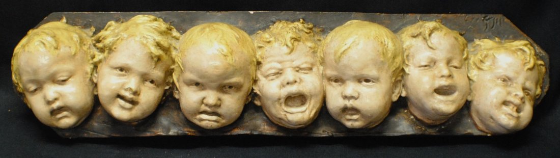 Plaster sculpture of 7 boys masks: Plaster sculpture of 7 boys masks 26 `1/2” x 6 ¼”, signed illegibly upper right.