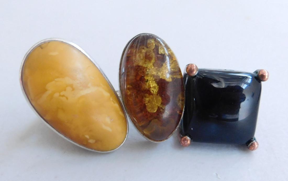3 Southwest Rings: 3 Southwest Rings, circa 1940s. Made of silver, amber, obsidian and copper, the items are approx. 1" x 1" x 1". Sizes are 7-7.25". Lot weight is 32.5 grams. Mexico, New Mexico. Condiition: Worn, see i