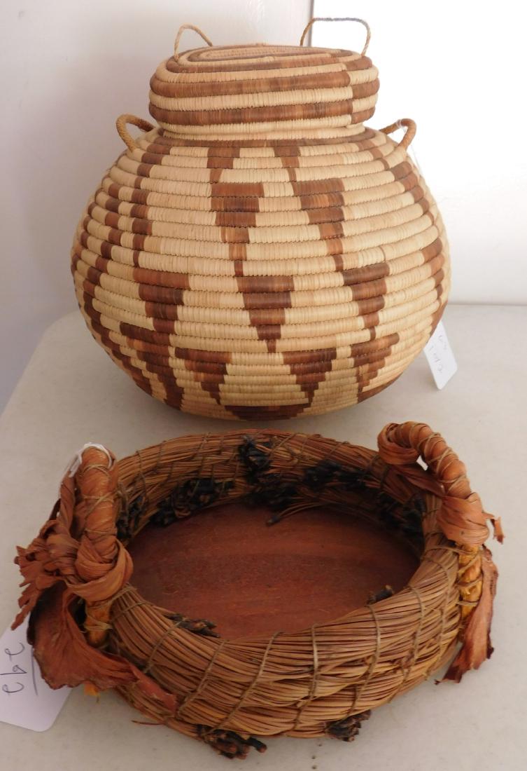 2 Tribal Baskets: 2 Tribal Baskets, c. 1950s. Made of grass, pine needles and wood, items measure 10" x 11" x 8" and 8" x 7" x 4". Southwest USA and Mexico. One is lidded, the other is open with handles. Condition: Min