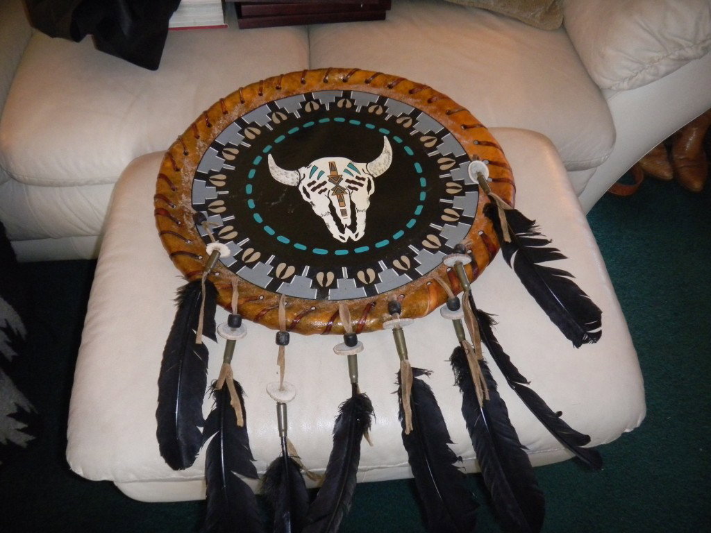 Navajo Hide Leather Dance Shield: Navajo Leather, elaborately painted dance shield with horn and antler and feather design, with 30 caliber shell casings. 20x2 inches excluding the feathers Shipping 30.00