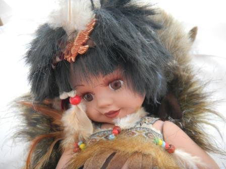 Porcelain Indian Doll Jointed: Porcelain Indian jointed doll by Duck House, This is a numbered doll. The doll is 13 x 5 inches and she comes with a simulated buffalo skin. Please note the bow and arrow, all the beadwork, the fancy
