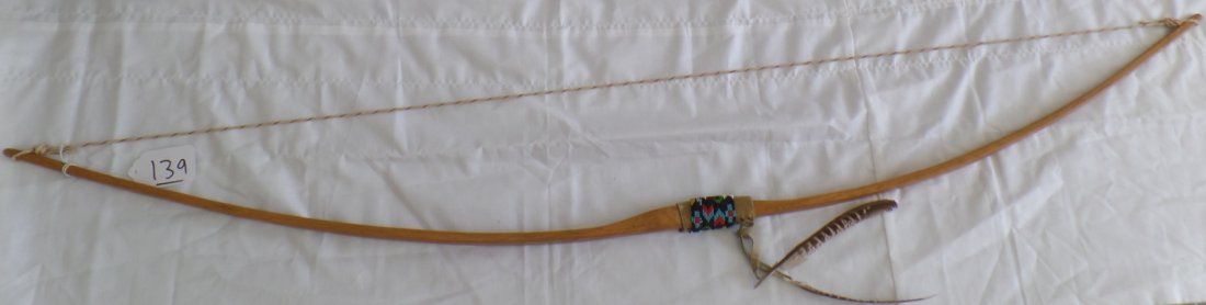 Native American Bow: Native American Bow measuring 58" long x 1.25" wide. Item is decorated with multi-colored beadwork, hide and feathers. Condition: Very Good. Shipping: $24.