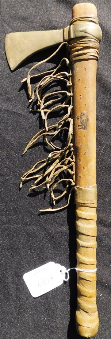 Plains Indian Tomahawk: Plains Indian Tomahawk, circa 1900's. It is made from rawhide, wood and brass. The item measures 20" x 6" x 2". This item was used in farewell ceremonies. Sioux, Dakotas. The handle has a buffalo and 