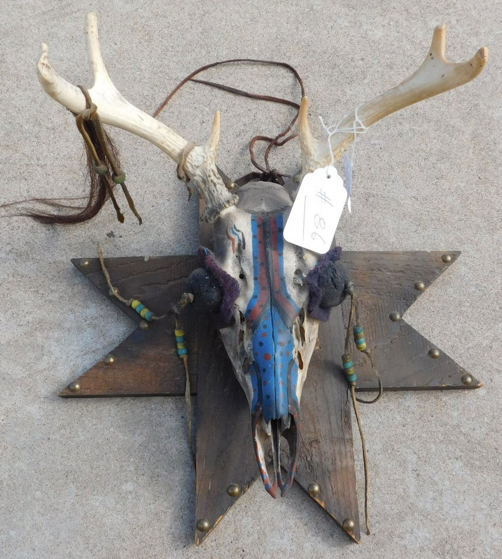 Plains Mounted Trail Marker: Plains Mounted Trail Marker, mid-20th century item. Made of deer skull, wood, beads, leather, and brass tacks. It has been painted red, black and blue. Sioux, South Dakota. Condition: There is some mi