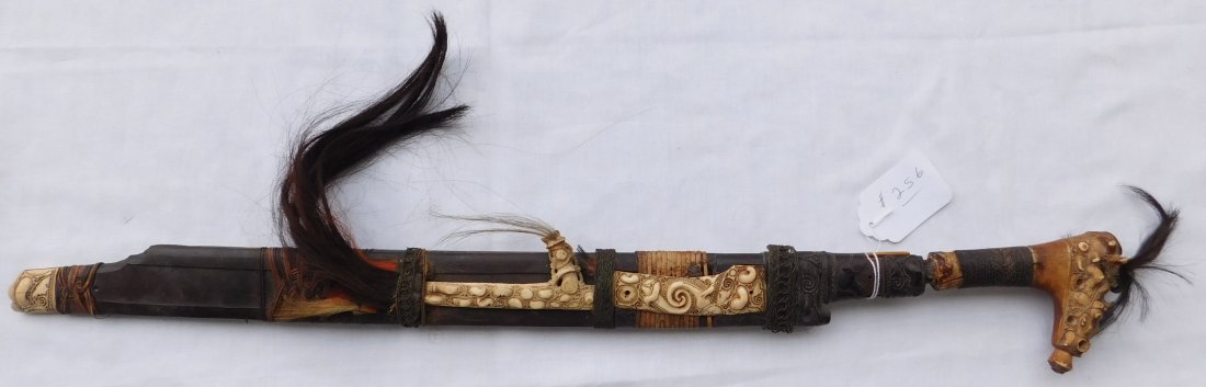Antique Dayak Mandau Sword from Indonesian: Antique Dayak Mandau Sword from Indonesian, circa 1750s. Made of bone, wood, steel, braided wire, hair, braided rattan and resin. Item measures 30" x 2.5" x 1". Dayak, Indonesia. Fancy wood carving on