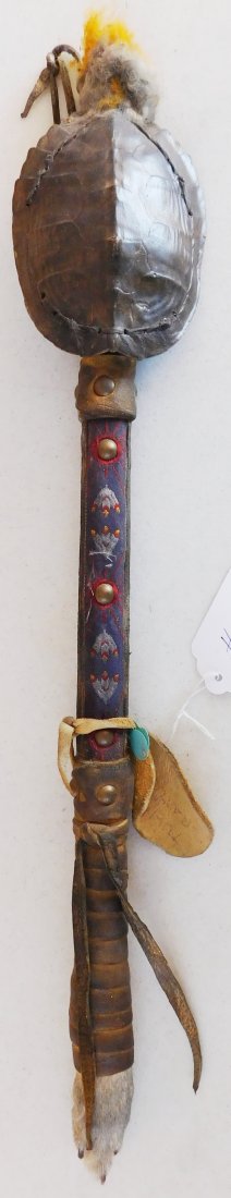 Plains Indian Turtle Rattle: Plains Indian Turtle Rattle, circa mid-20th century. Item measures 24 x 4 x 2 inches. This rattle is made from rabbit foot fur, metal bells, rawhide, brass tacks and turtle shell. See finely sewn desi