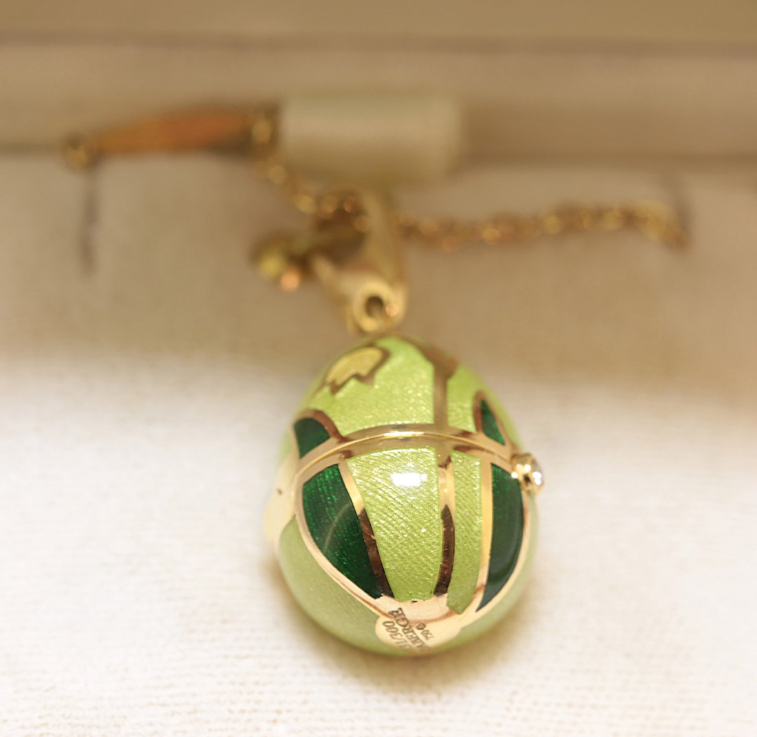 FABERGE "EGG" PENDANT AND NECKLACE: 196. FABERGE "EGG" PENDANT AND NECKLACE Stamped Faberge, 750 and numbered 356/500. The egg decorated with flowers, hinged with a round diamond, opening to a bird on a branch. Weighing approximately 28