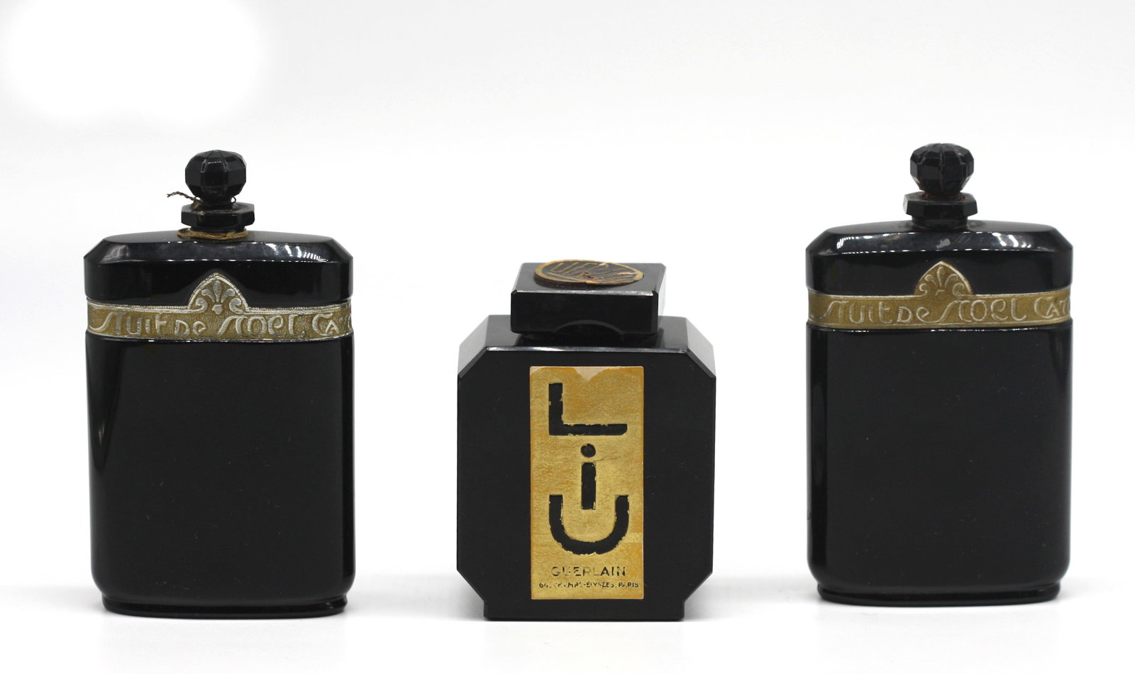 Three French Art Deco Black Glass Perfume Bottles.: Three French Art Deco Black Glass Perfume Bottles.The first, Guerlain Liu, produced in 1929, underside etched Guerlain Made in France and with paper labels, square with canted corners and square stopp