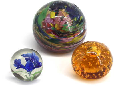 Three Variously Decorated Glass Paperweights: Three Variously Decorated Glass Paperweights The first, signed Navaro, dated 1992, is internally multicolored, the second, amber with controlled bubbles, the third, with four cornflower blue flowers.