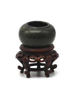 Chinese Qing Dynasty Spinach Jade Cosmetic Jar: Chinese Qing Dynasty Spinach Jade Cosmetic Jar 19th Century. The black veined dark green compressed spherical jar with a molded rim and raised foot, on a carved wood stand. Height 1.25 in.,