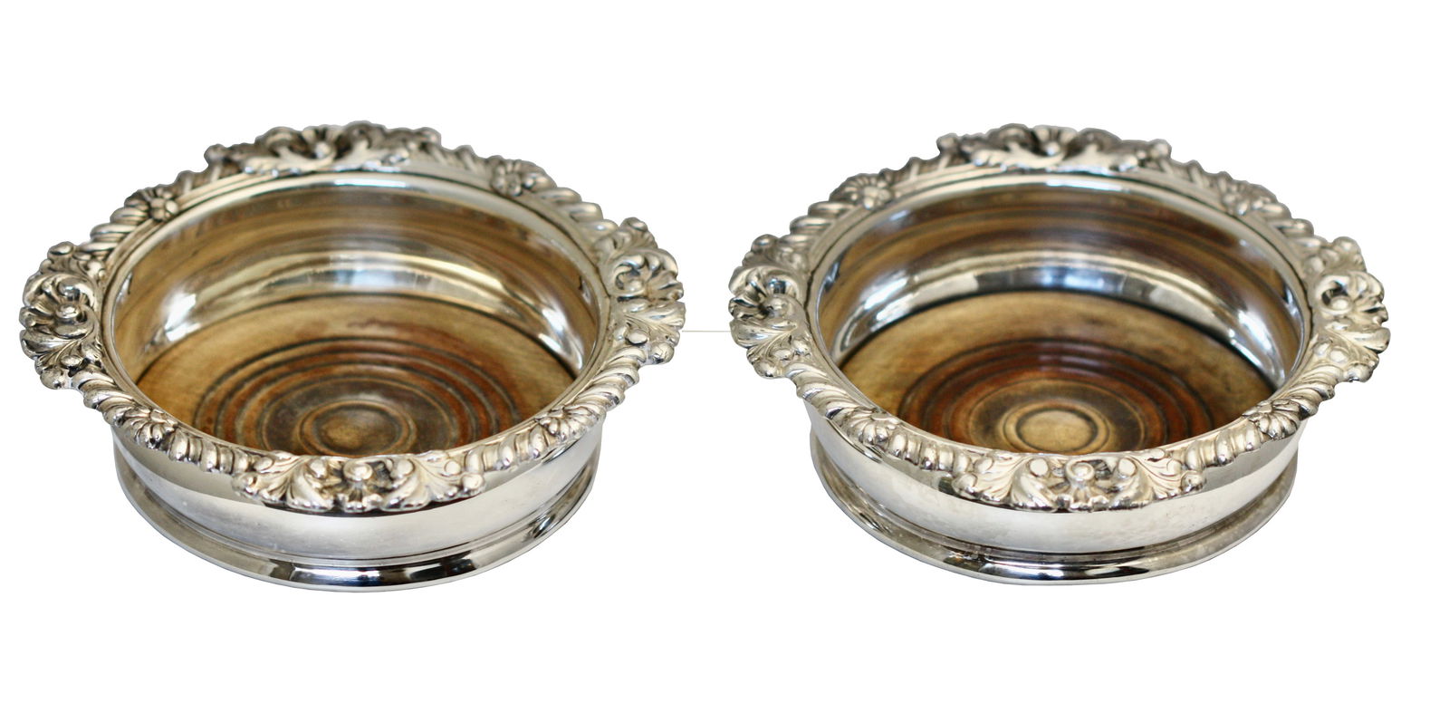 Pair of English Silver Plate Bottle Coasters: Pair of English Silver Plate Bottle Coasters Unmarked, each with a leaf and shell cast gadrooned scalloped edge, with wooden bottoms. Height 2 in., Diameter 6.75 in.