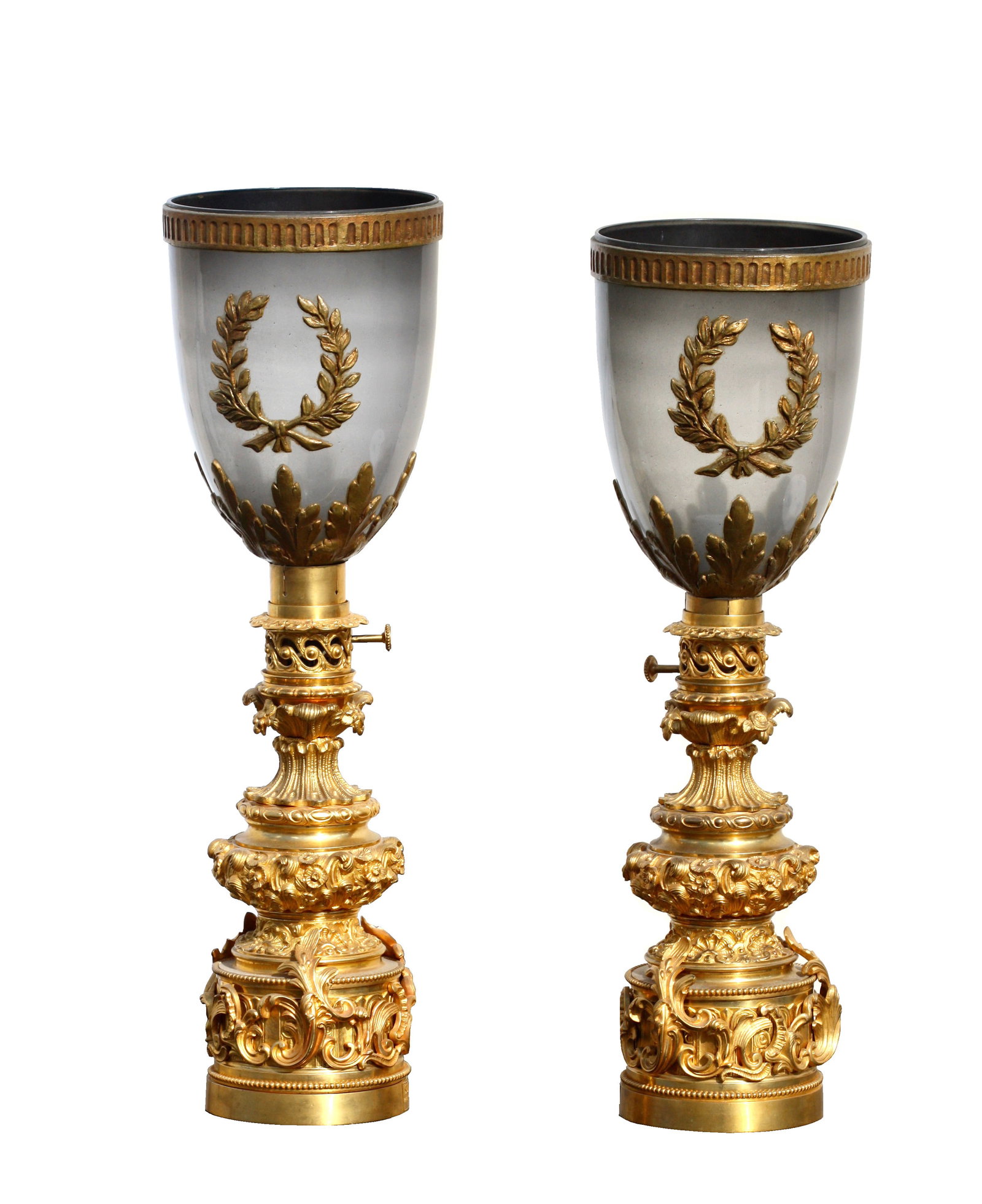 Pair of French Gilt Bronze and Wood Hurricane Lamps: Pair of French Gilt Bronze and Wood Hurricane Lamps. In the Restauration style, cast allover with stylized foliage and neoclassical motifs, the smokey glass shades with giltwood appliques, fitted for 