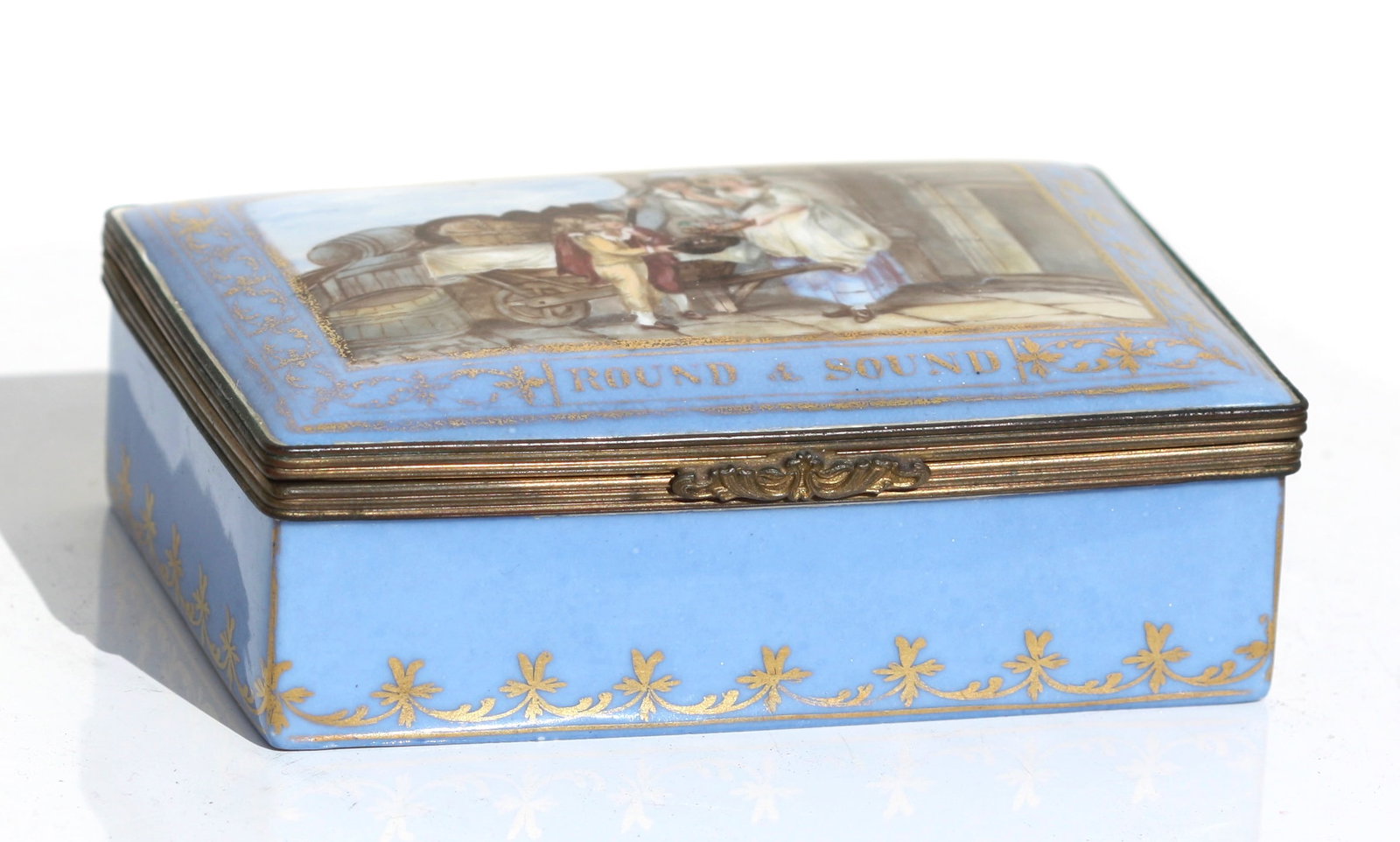 English Parcel Gilt and Painted Porcelain Box: English Parcel Gilt and Painted Porcelain Box Mid to late 19th Century. The rectangular hinged cover painted with a figural panel and inscribed, Round and Sound. Length 5 in. (12.7 cm.)