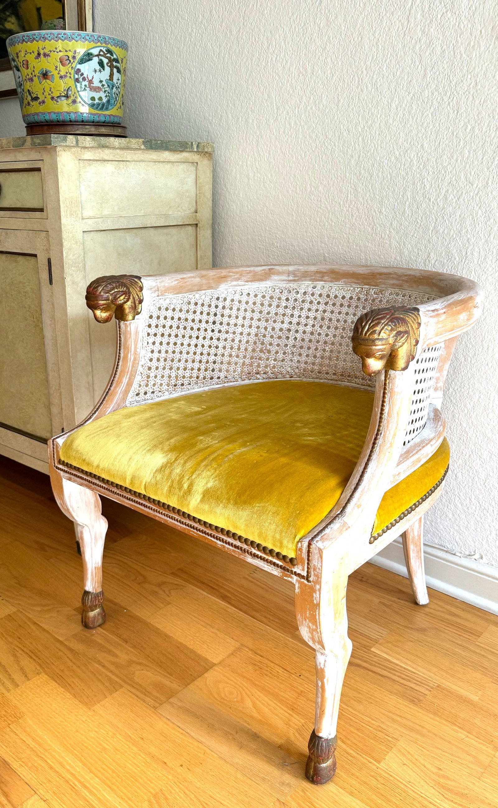 Pair, Regency Style Painted & Part Gilt Cane-Back Tub Chairs: Pair of Regency Style Painted & Partial Gilt Cane-Back Tub Chairs with rams heads and animal-form legs ending in hoofed feet, each with deliberately distressed white paint. Height 25.5 in., Width 23 i