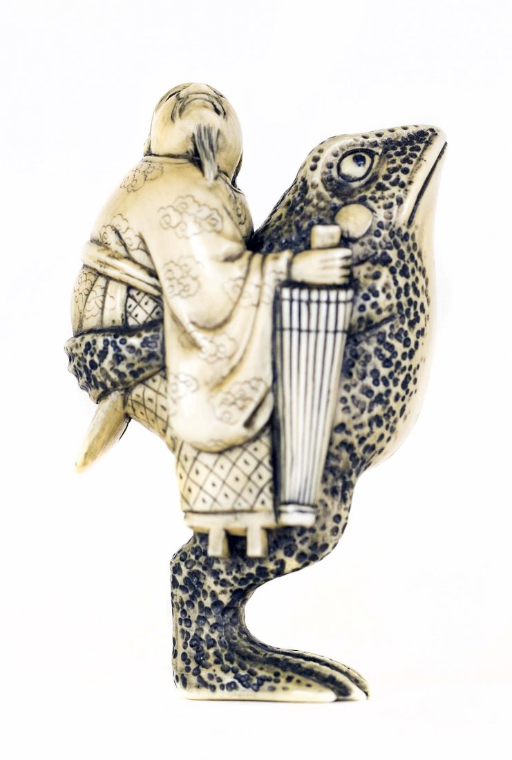 CARVED IVORY NETSUKE: PROPERTY FROM A FLORIDA COLLECTION CARVED IVORY NETSUKE Signed. Of a mythological frog, carrying a man holding an umbrella on its backside. (Legend of the Ono no Tofu) Height 2 1/4 inches.