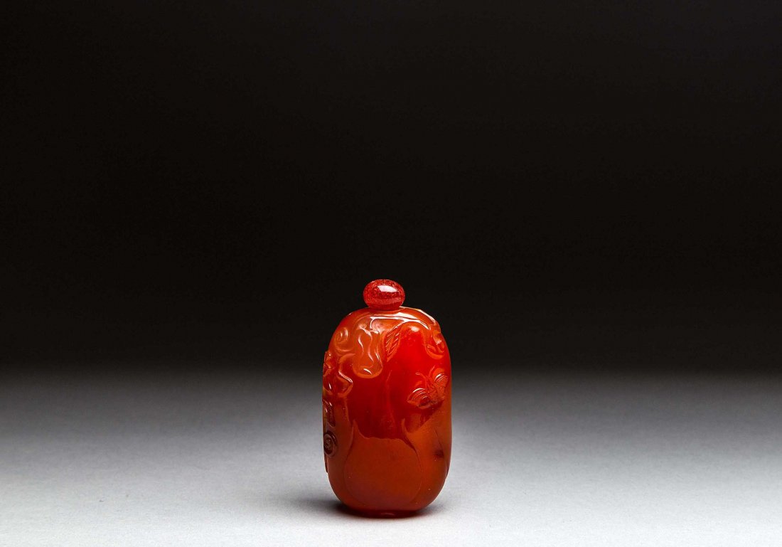 CHINESE CARVED CARNELIAN SNUFF BOTTLE AND STOPPER: CHINESE CARVED CARNELIAN SNUFF BOTTLE, of oval fruit form subtely carved with flowers and butterflies. Height 3 in.