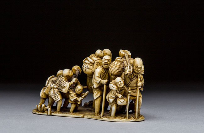 JAPANESE CARVED IVORY NETSUKE/OKIMONO, MEIJI PERIOD: VERY FINE JAPANESE CARVED IVORY NETSUKE/OKIMONO, MEIJI PERIOD Carved as ten figures fording a stream, late 19th century; signed Shunzan. Length: 2 1/2 in. (6.35 cm.)