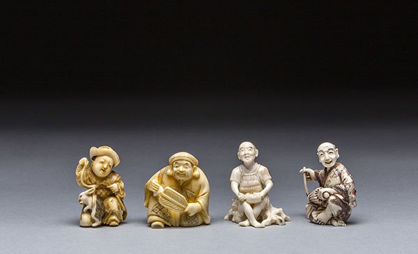 FOUR CARVED IVORY NETSUKE: FOUR CARVED IVORY NETSUKE The first netsuke of a boy with a rabbit, the second netsuke of a man seated with a fan, the third netsuke of a boy seated with a book; signed with a red lacquer reserve, the