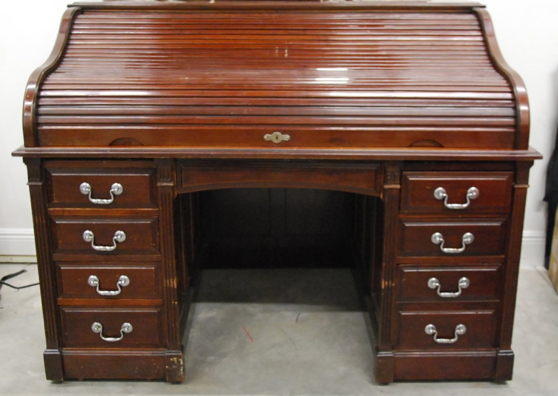 LARGE MAHOGANY ROLL-TOP DESK AND LEATHER ARMCHAIR: LARGE MAHOGANY ROLL-TOP DESK AND A LEATHER ARMCHAIRearly to mid 20th century, probably English, the roll top opening to an interior fitted with drawers, above two pedestals each with four drawers surr