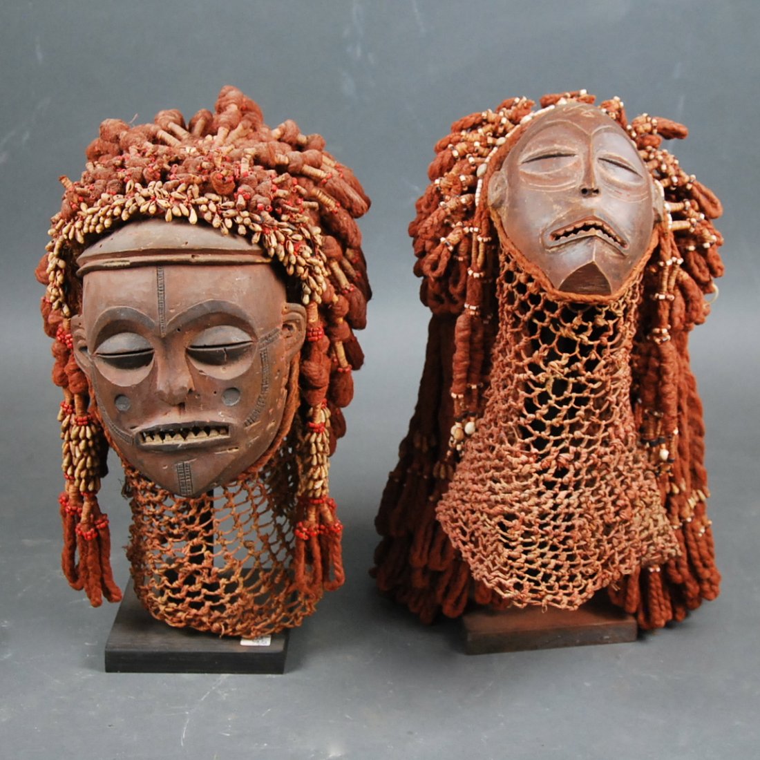 PR RED PIGMENTED AND HEMP MALE & FEMALE AFRICAN MASKS: PAAIR OF FINE MALE AND FEMAL CENTRAL AFRICAN MASKS Modern, each full faced mask well carved and decorated with long hemp woven hair, the hair and face with red pigment. Height 18 in , 16 in.