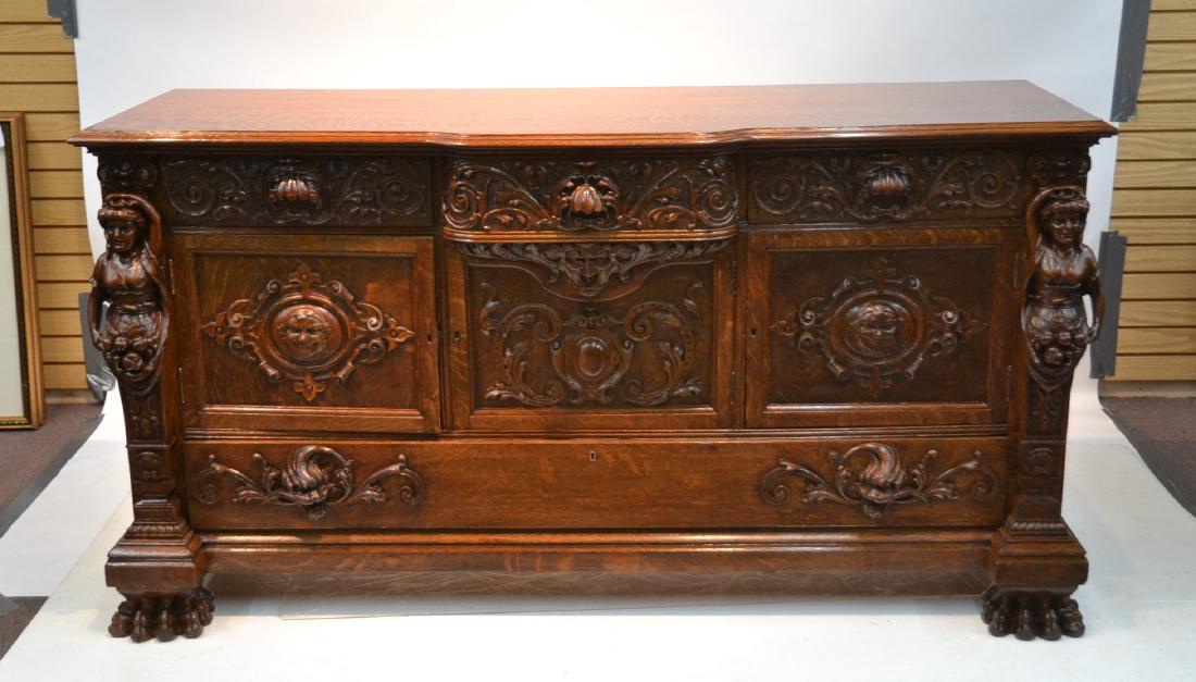 LARGE HEAVILY CARVED TIGER OAK SIDEBOARD: WITH CARVED FACE OF THE WIND , CARYTIDS & MASKS RAISED ON PAW FEET - 72" x 25" x 38"