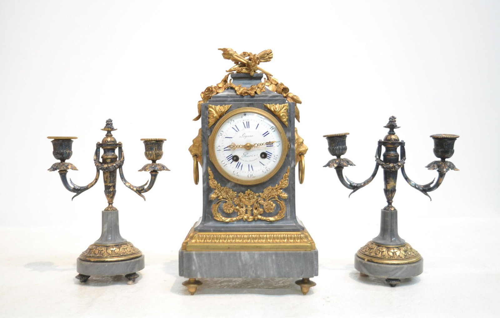 (3)pc LEPINE A PARIS , BRONZE & MARBLE CLOCK SET: BRONZE & MARBLE CLOCK WITH TORCH & ARROW ATOP SURROUNDED BY LION DROP RING HANDLES & MATCHING (Pr) GARNITURE , FACE MARKED LEPINE A PARIS , WITH JAPY FRERES MOVEMENT - CLOCK IS 7 1/2' x 5 1/4" x 14" ;