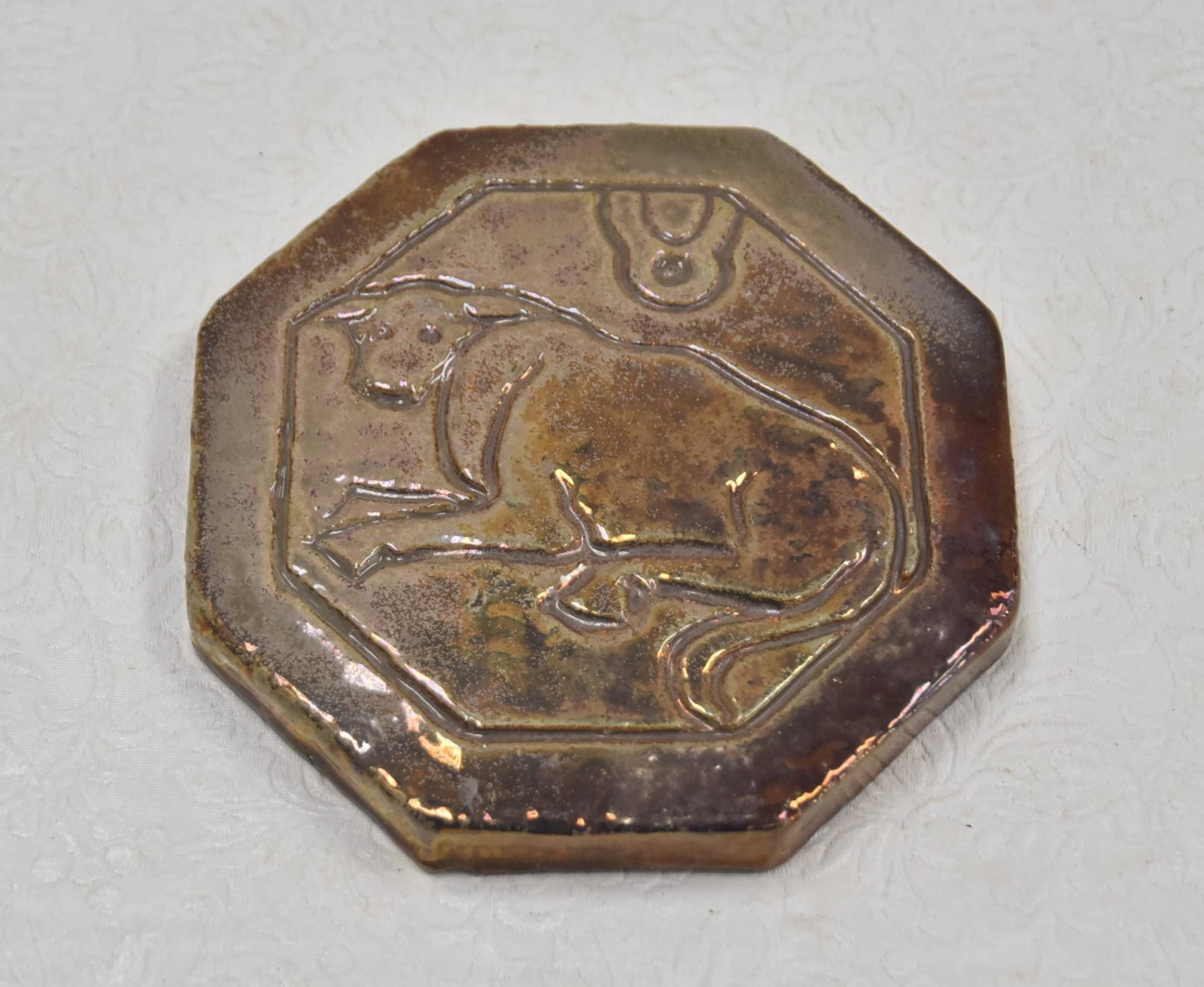 PEWABIC , DETROIT POTTERY IRIDESCENT TILE: IRIDESCENT OCTAGONAL PEWABIC POTTERY TILE WITH INCISED COW , SIGNED & WITH LABEL - 6" x 1"