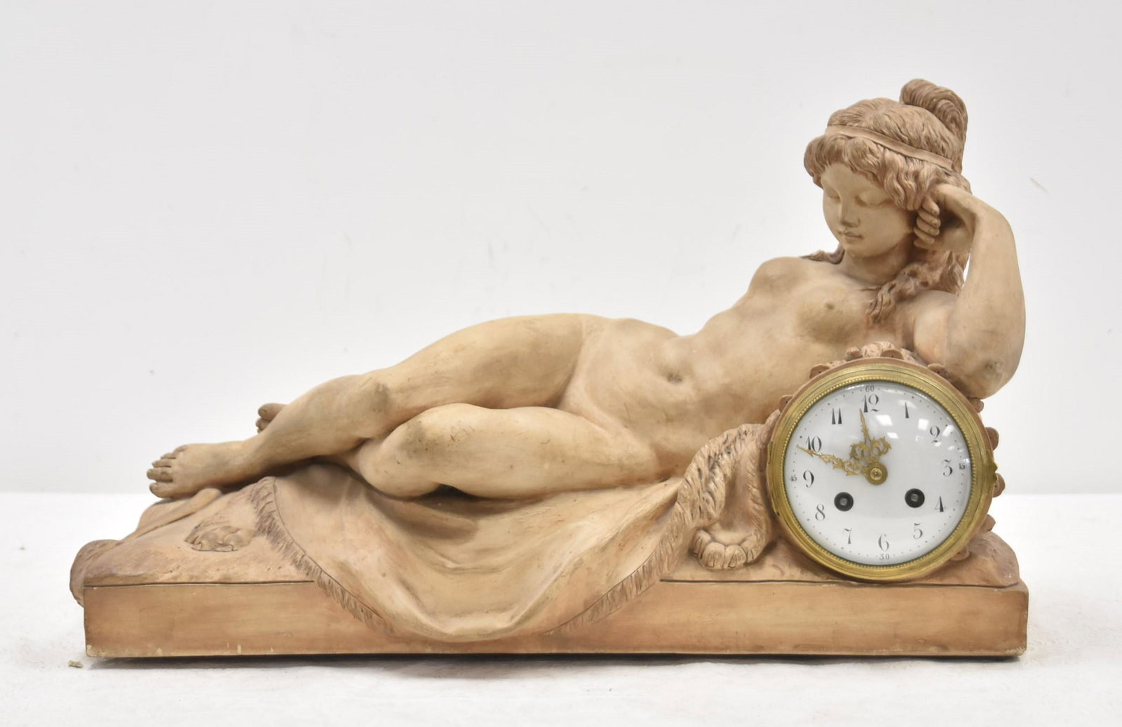 SEVRES TERRACOTA BACCHANTE CLOCK AFTER CLODION: FRENCH SEVRES TERRACOTTA CLOCK DEPICTING RECLINING NYMPH BACCHANTE LAYING ON LION PELT WITH INSET CLOCK , TITLED "LA SOURCE" ; AFTER MODEL BY CLAUDE MICHEL CLODION - 9" x 20" x 13 1/2"