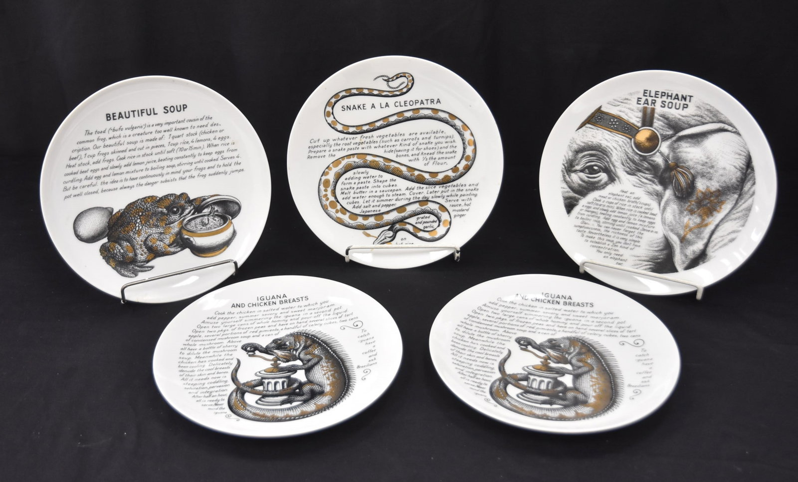 (5) FORNASETTI COOK PLATES: (5) PIERO FORNASETTI , MILANO ITALY RECIPE PLATES "SNAKE A LA CLEOPATRA: , (2) IGUANA & CHICKEN BREAST ,"ELEPHANT EAR SOUP" & "BEAUTIFUL SOUP" ; FLEMING JOFFEE LTD COOK PLATES , PIERO FORNASETTI - 10"