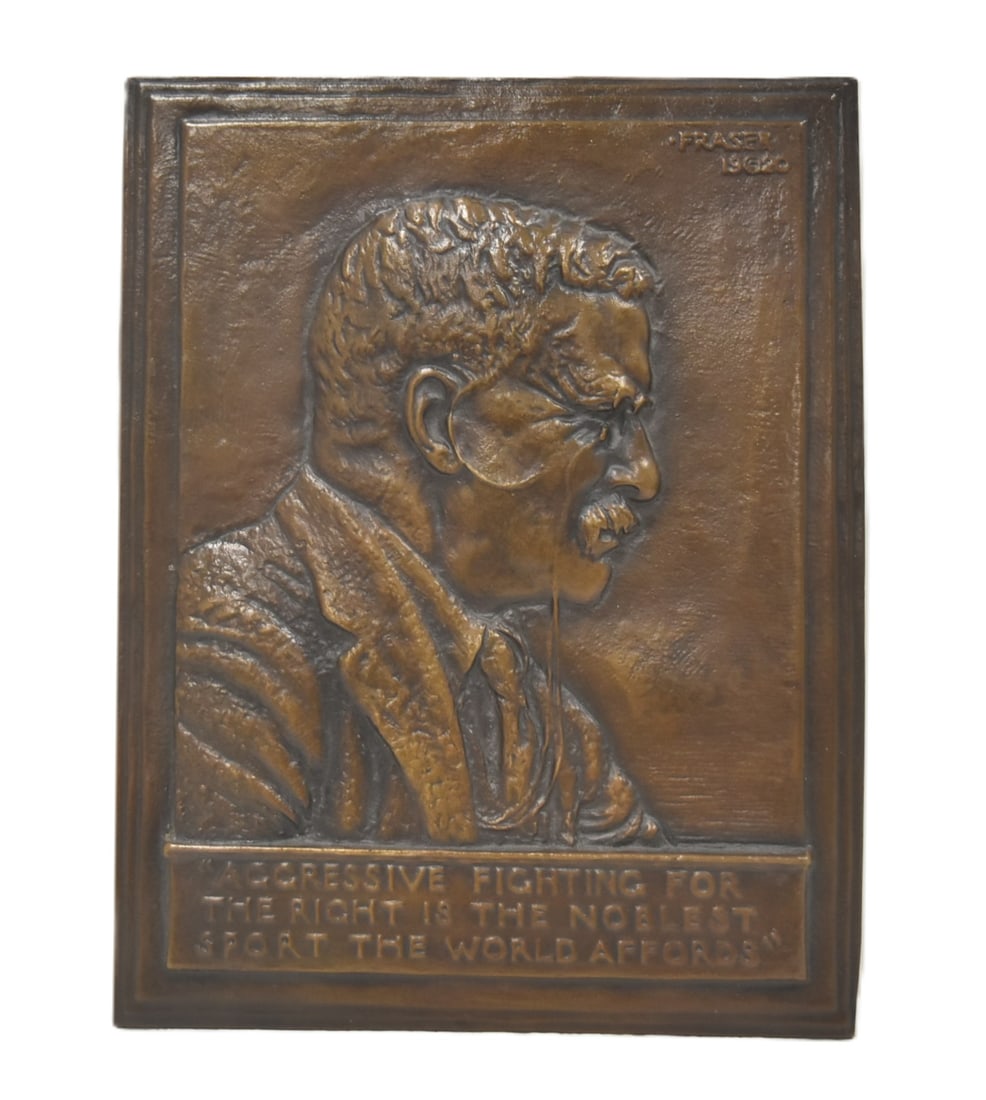 JAMES EARLE FRASIER BRONZE TEDDY ROOSEVELT PLAQUE: JAMES EARLE FRASER (AMERICAN, 1876-1953) CAST BRONZE BAS-RELIEF THEODORE ROOSEVELT MEMORIAL WALL PLAQUE, rectangular form, featuring a right-facing shoulder-length bust of Teddy Roosevelt above the qu
