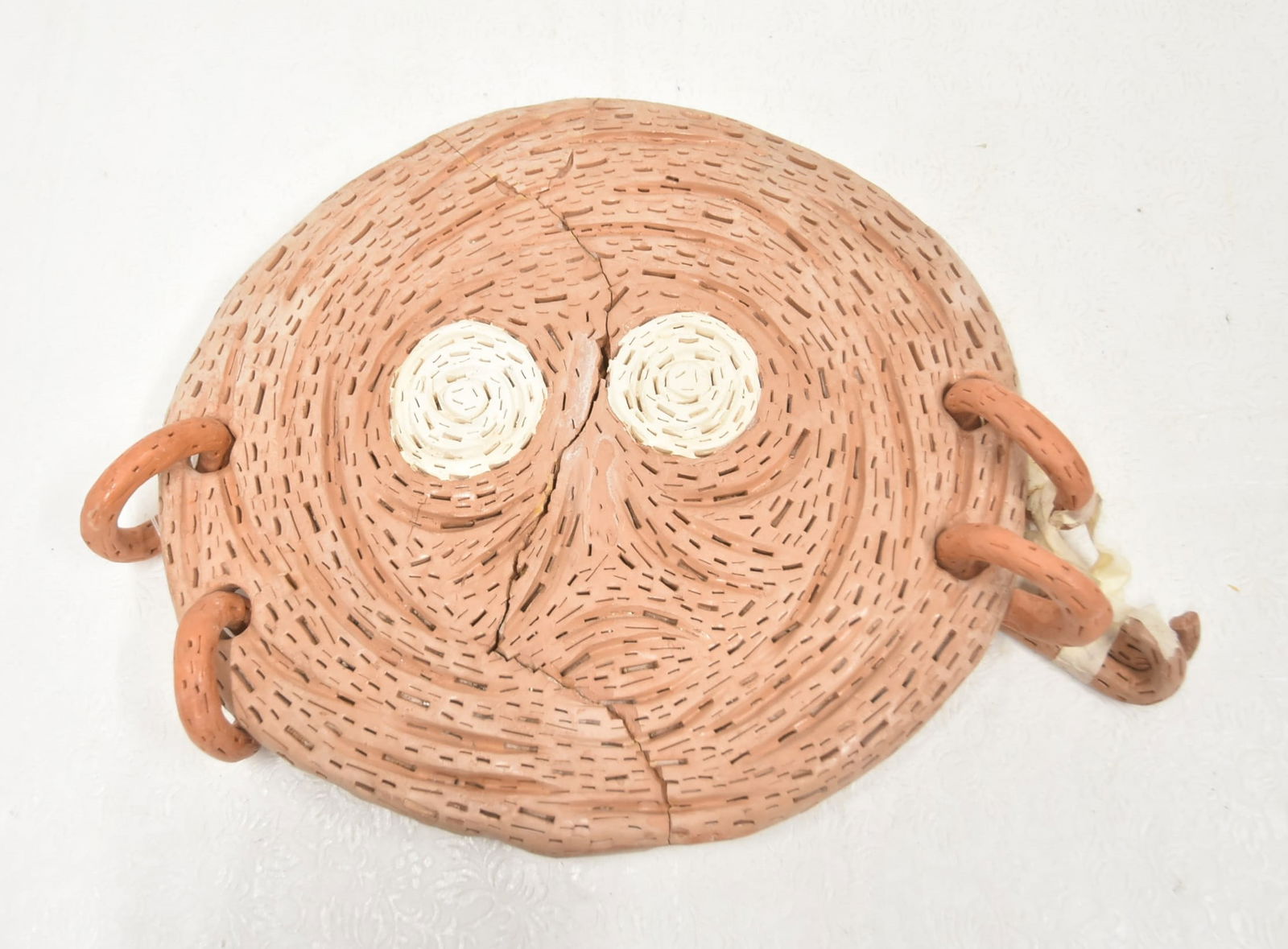 ALEXANDER NEY ROUND FACE SCULPTURE: ALEXANDER NEY (RUSSIAN / AMERICAN, b. 1939) RETICULATED TERRACOTTA SCULPTURE OF FLAT ROUND FACE WITH DROP RINGS - 15 1/2" D (SOME LOSS)