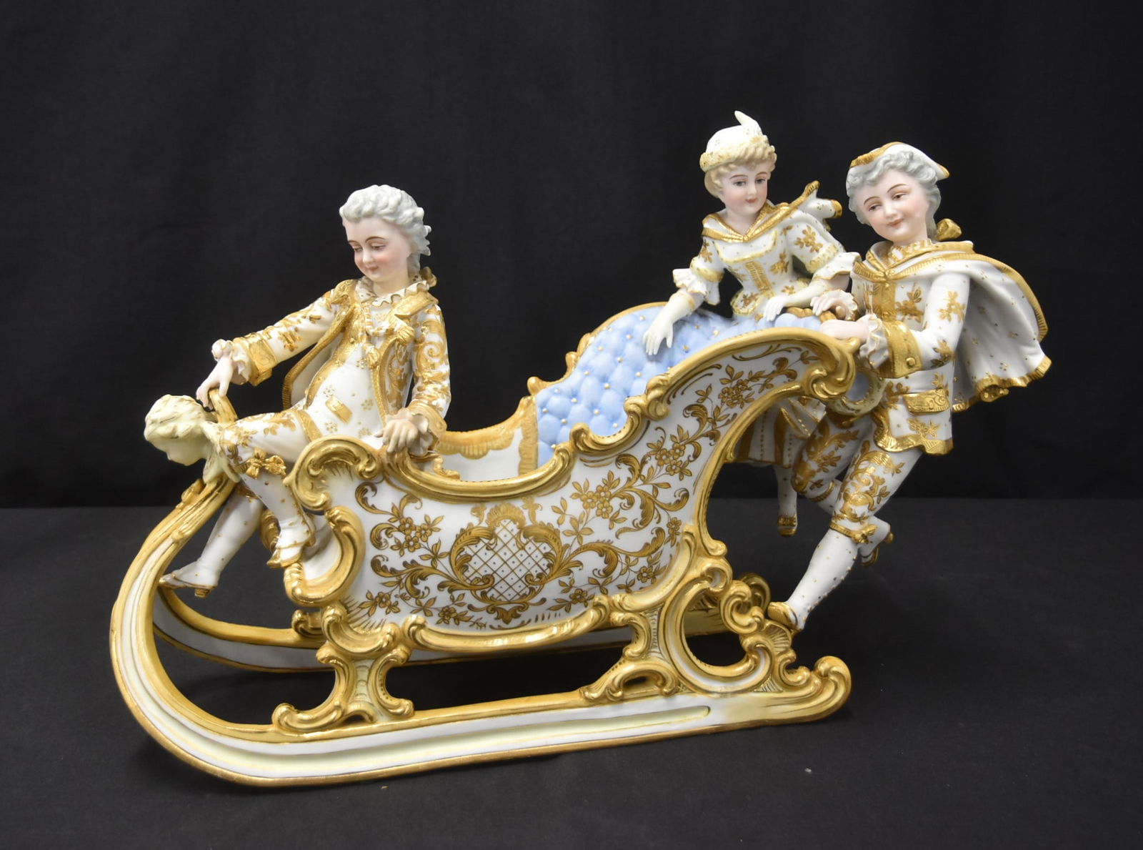 LARGE SITZENDORF BISCUIT PORCELAIN CENTERPIECE: ANTIQUE SITZENDORF BISCUIT PORCELAIN FIGURAL SLEIGH FORM CENTERPIECE WITH FIGURES AROUND SLIEGH FORM PLANTER CENTERPIECE WITH HEAVY GOLD DECORATIONS , ca. 1900 - 19 1/4" x 11 3/4" x 8"