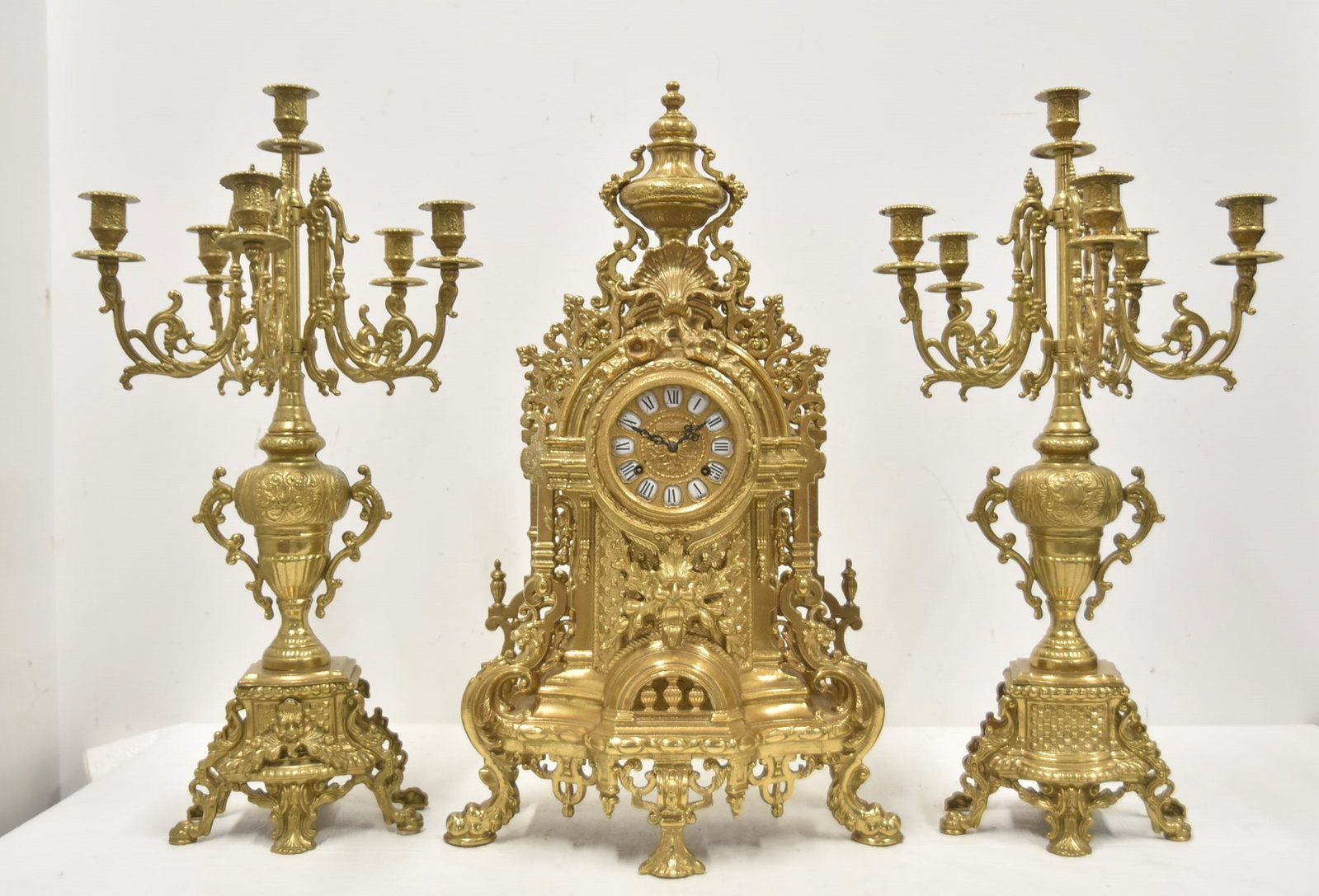 (3)pc GERMAN IMPERIAL BRASS CLOCK SET: (3)pc FRANZ HERMLE GERMAN MOVEMENT MANTEL CLOCK SET WITH MATCHING PAIR CANDELABRAS ; ORNATE ITALIAN FRENCH STYLE BRASS CASE WITH ROMAN NUMERALS - CLOCK IS 14" x 6" x 24" ; CANDELABRAS ARE 12" x 24" ;