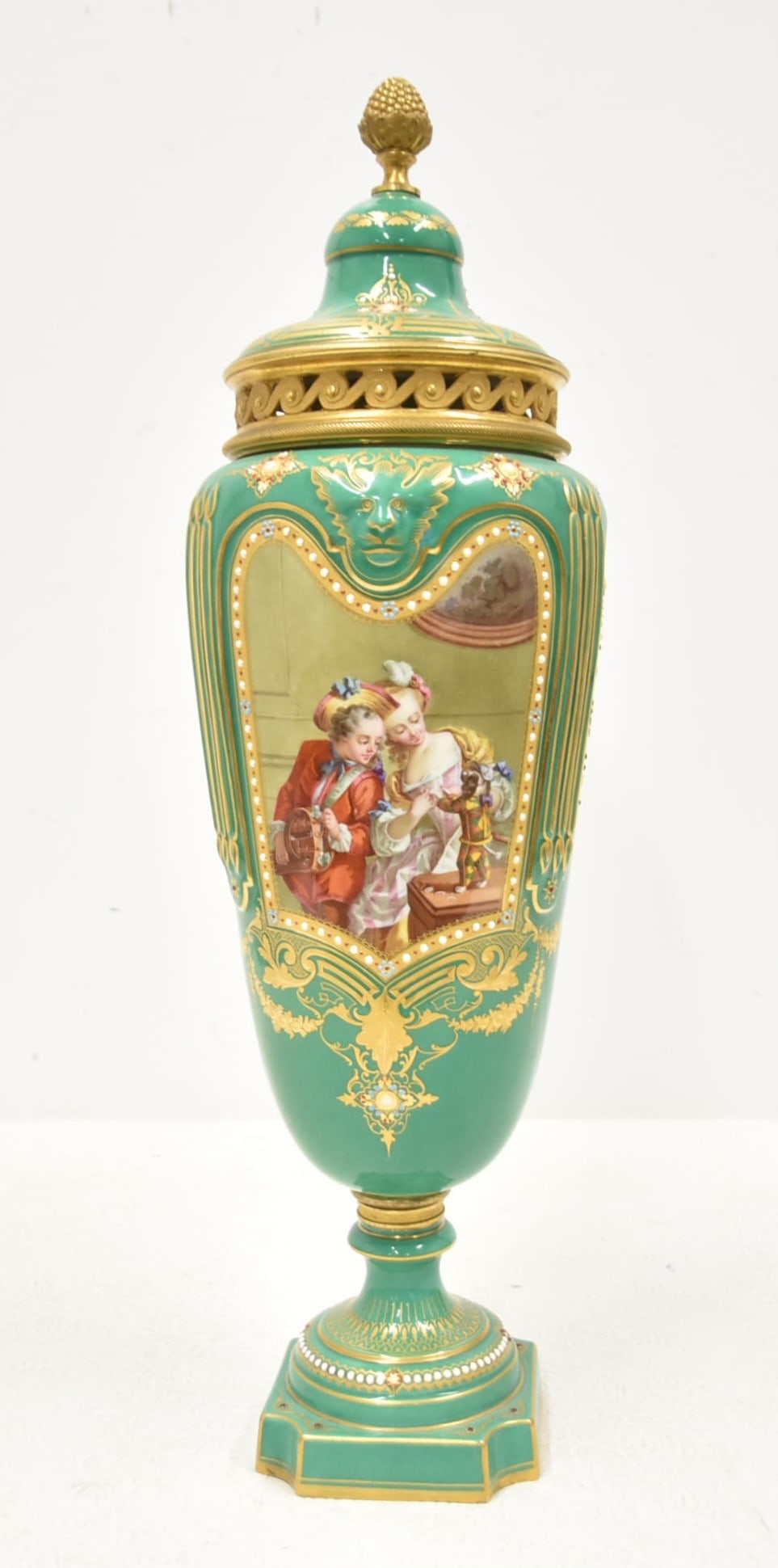 FINE HAND PAINTED SEVRES JEWELED POTPOURRI URN: HAND PAINTED SEVRES FOND VERTE COVERED POTPOURRI URN WITHH HAND PAINTED SCENE OF MAN & WOMAN PLAYING WITH DOG DRESSED AS BABY ; HAVING LANDSCAPE SCENE INVERSO SURROUNDED BY ENAMEL JEWELS & HEAVY GOLD 