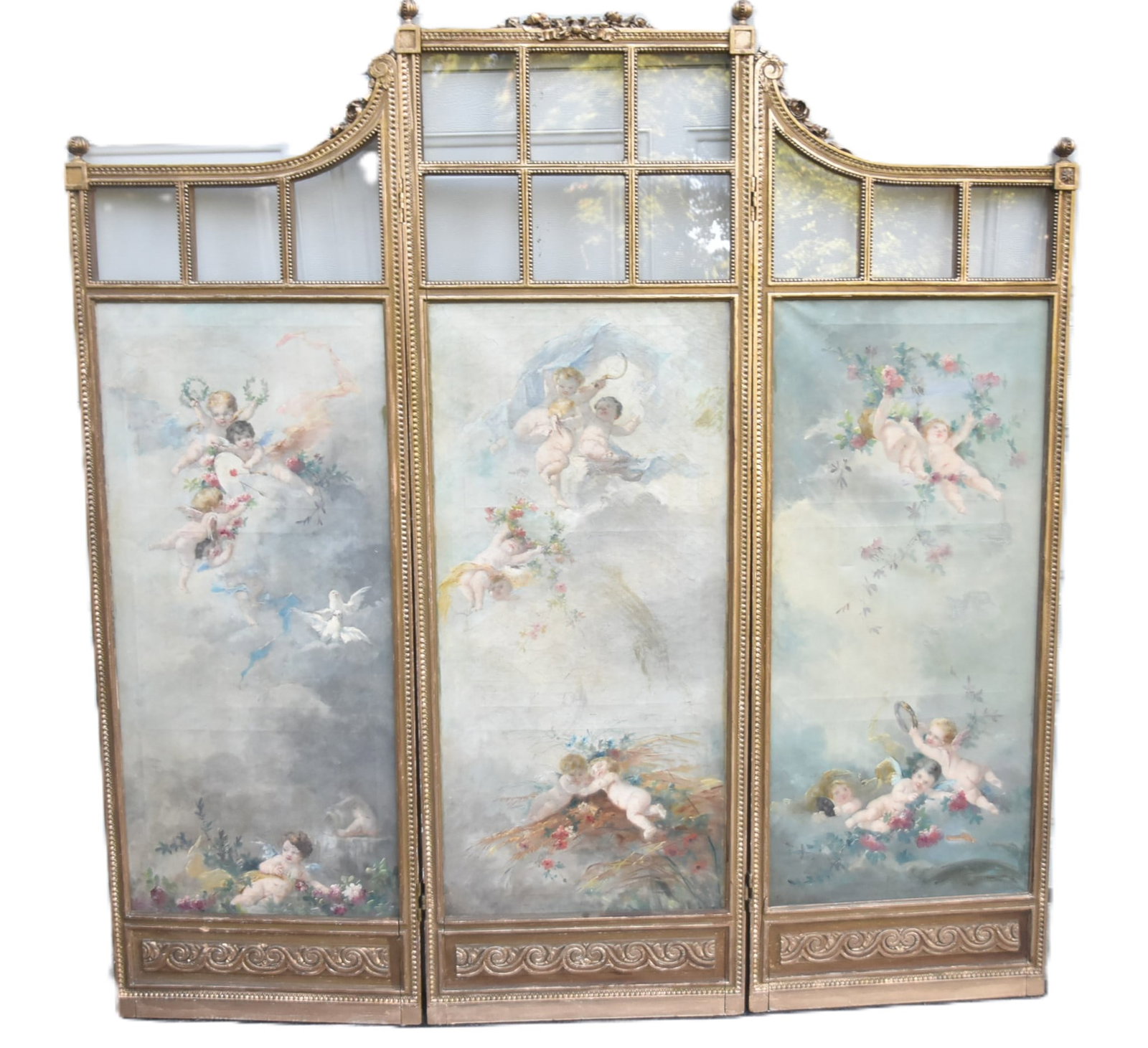 FRENCH LXVI GILTWOOD PAINTED CHERUB FLOOR SCREEN: FRENCH LOUIS XVI GILTWOOD 3-PANEL ROOM DIVDER SCREEN WITH (3) CHERUB OIL ON CANVAS PAINTINGS DEPICTING CHERUBS FROLICKING IN THE HEAVENS ; WITH GLASS PANELS - 67" x 69" (PLEASE NOTE THIS ITEM IS BEING