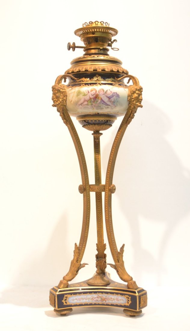 COBALT SEVRES BANQUIT OIL LAMP WITH HAND PAINTED: CHERUB SCENES OVER COBALT GROUND SUPPORTED BY 3-BRONZE SATYR LEGS WITH HOOF FEET WITH DUPLEX BURNER (SOME CRACKS ON PORCELAIN) 10" x 29"