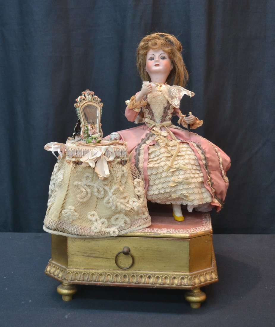 AUTOMATON SEATED BISQUE HEAD DOLL AT DRESSING: TABLE WITH MIRROR & ACCESSORIES ; AUTOMATON FEATURES GIRL POWDERING NOSE AND BRING HAND MIRROR TO UP TO FACE ;WITH DRAWER OPERATING THE OFF FOR WIND UP MUSIC- 8" x 9" x 15"