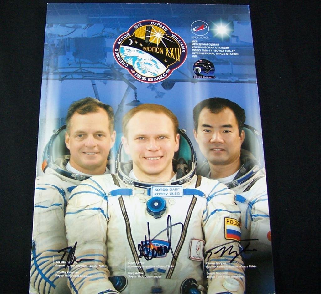 Expedition 22 Crew-Signed Russian Mission Book: An 8"x 11.75" Expedition 22 crew-signed color booklet and signed on the cover by all three cosmonauts / astronauts with authentic signatures. The booklet contains 116 pages of color photos and informa