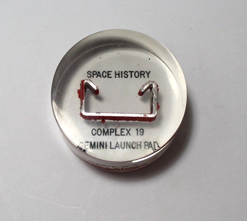 Gemini Launch Complex 19 Section in Lucite: A 2.75" diameter by 1.5" thick lucite containing a 1.75" metal fragment from Gemini Launch Complex 19. Excellent condition.