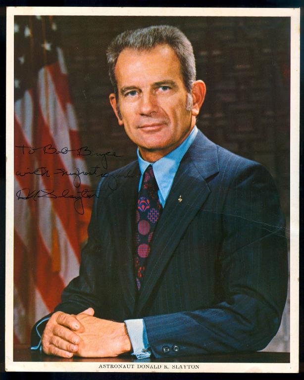 Deke Slayton Signed NASA Color Litho: An 8"x 10" NASA color litho signed by Apollo-Soyuz astronaut Deke Slayton. Some minor age spotting on the bottom white margin. Masking tape stains on the back from being taped to the matte. A crease e