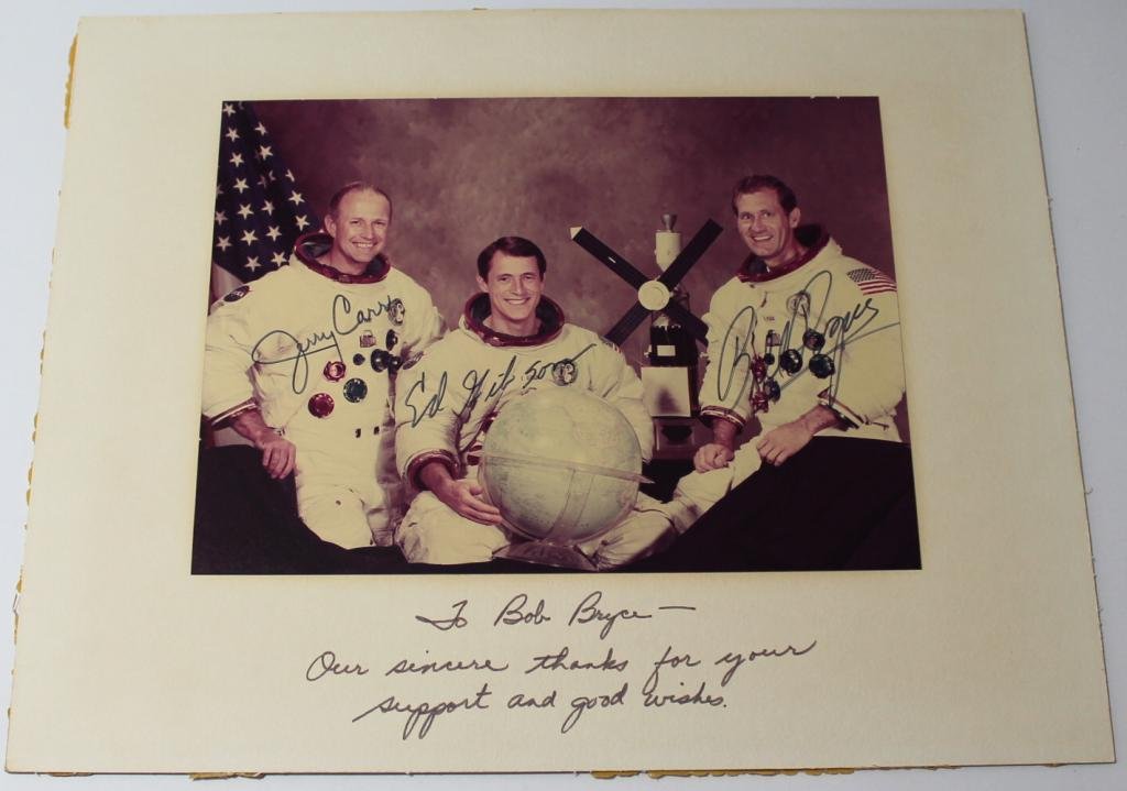 Skylab 4 Crew-Signed Matted Photo: A 7"x 9.5" glossy photo of the Skylab 4 crew attached to an 11"x 14" matte board, and signed by Carr, Gibson and Pogue. The photo is a bit faded from being displayed for years, but still overall great