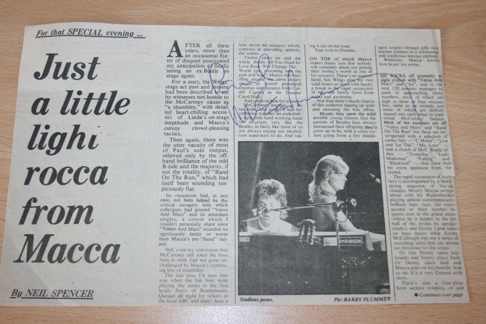 PAUL McCARTNEY: PAUL McCARTNEY - Newspaper article reviewing Wings' live tour, signed in blue pen over the text by Paul McCartney. Article features black and white photo of Paul and Linda playing live together. Item 
