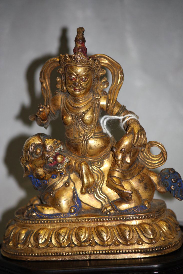 Antique Gilt Bronze Figure of Jambhala: Antique Gilt Bronze Figure of Jambhala 18 th Century, seated on a lion over a lotus base, his right hand in vitarkamudra with his left hand holding a mongoose dressed with festooned robe. H: 4.5 Inche