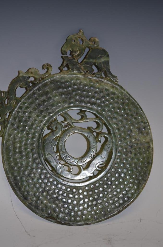 Carved Green Jade Bi WIth Open Work: Carved Green Jade Bi decorated with heraldic dragons- two on the outer rim, a third crawling around a small inner disc in the center. Surface of disc is decorated with raised rows of spirals to form g