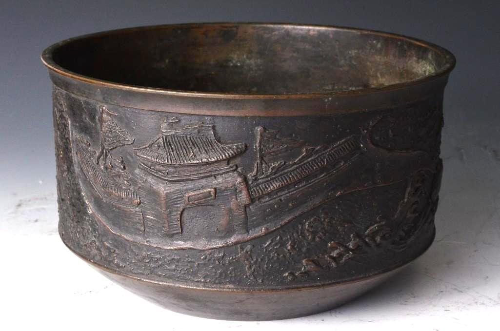 Antique Bronze Chinese Planter: Antique Bronze Chinese Planter incised with the six character Ming dynasty seal mark to the base decorated in low relief depicting a scene of a traditional Chinese town scene; D: 7 Inches